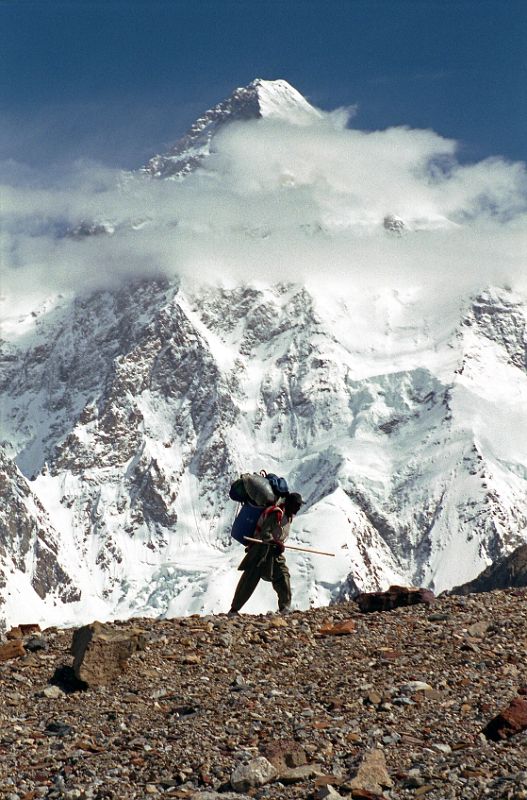 05 Sirdar Ali Naqi On Upper Baltoro Glacier With K2 Behind Sirdar Ali Naqi walks along the Upper Baltoro Glacier with K2 behind.